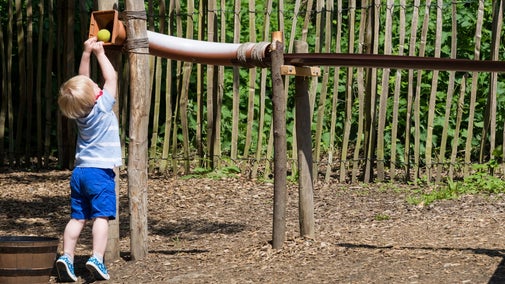 A small child playing with the ball chute in the Badger & Pepper play area at Scotney Castle